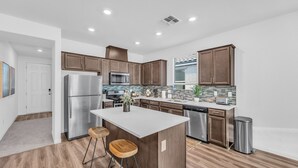 Una cocina moderna con armarios de madera, electrodomésticos de acero inoxidable y una isla central con taburetes.