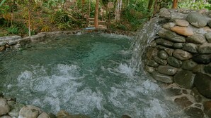 A hot spring with a stone wall and a waterfall. - Oasis Diverse Adult Retreat. (Quepos)