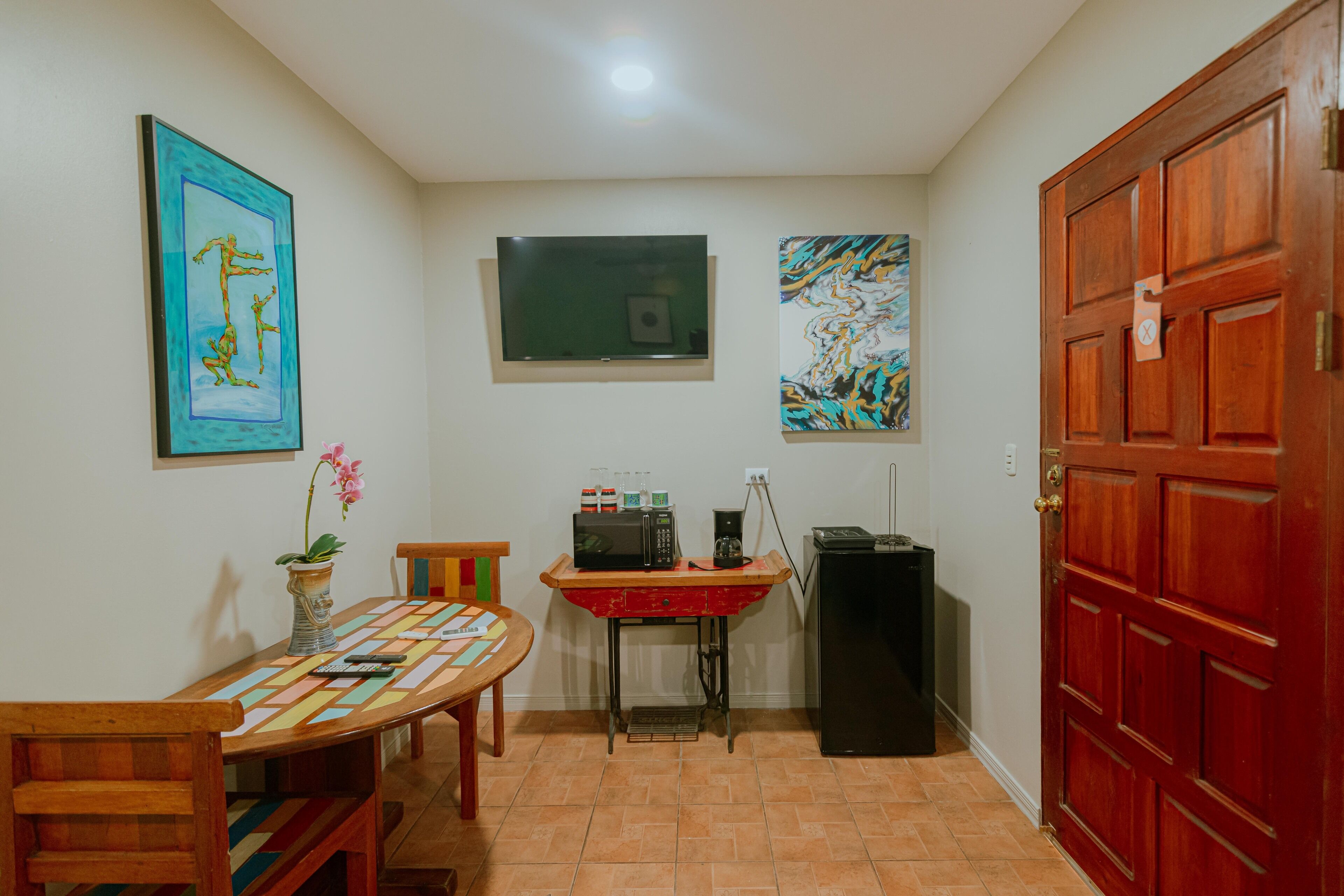 Uma cozinha compacta com mesa, cadeiras, micro-ondas, cafeteira e geladeira.