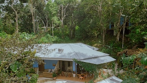 A house surrounded by dense vegetation, with a covered patio area and outdoor seating. - Oasis Diverse Adult Retreat. (Quepos)