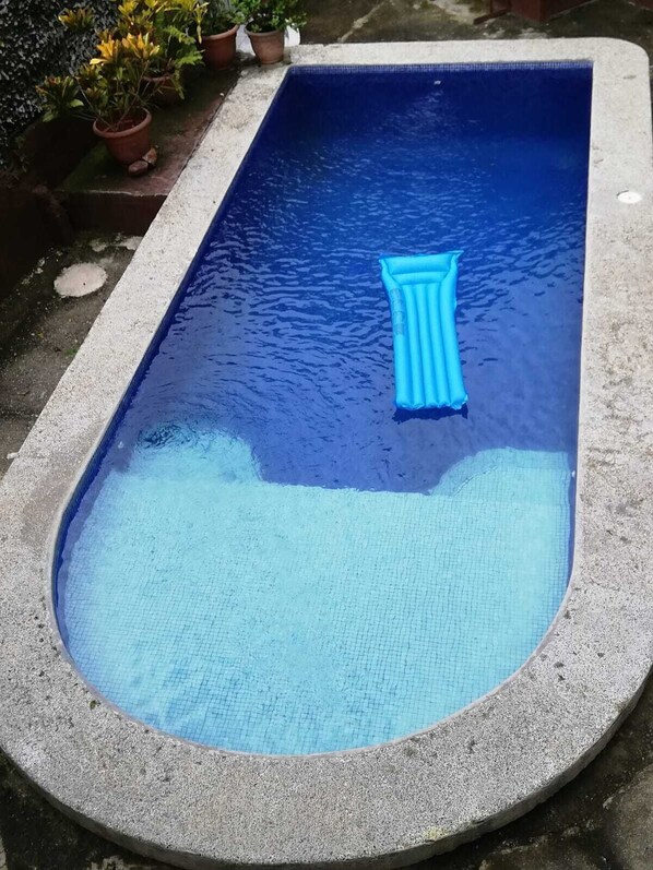 A rectangular pool with a blue inflatable float, surrounded by a concrete edge. - Oasis Diverse Adult Retreat. (Quepos)