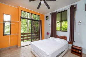 A bedroom with a bed, a ceiling fan, a window with curtains, and a view of greenery outside. - Oasis Diverse Adult Retreat. (Quepos)