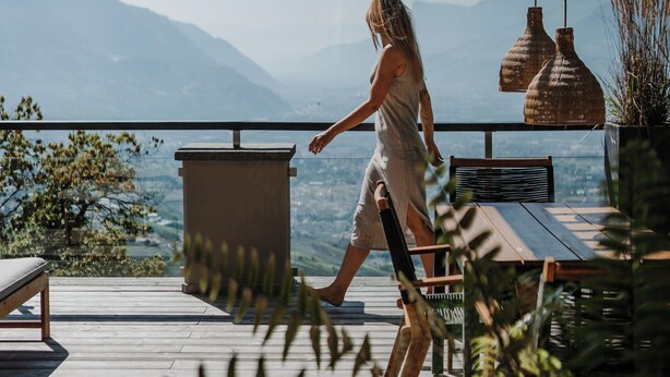 A woman walking on a wooden deck with a view of mountains and a lake. - Ruhiges Loft in der Natur mit Fantastischem Blick auf Meran (Dorf Tirol)