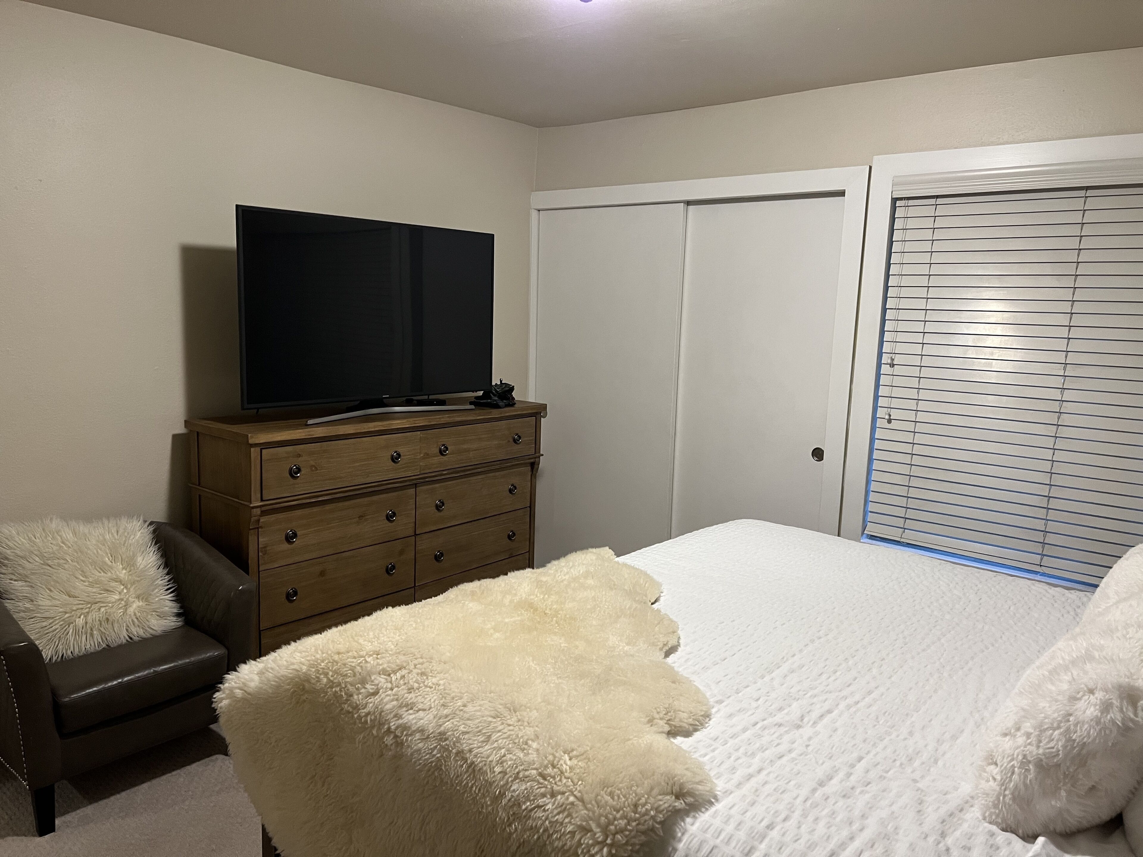 A bedroom with a bed, a dresser, a television, and a closet.
