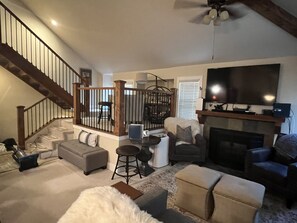 A spacious living room with a fireplace, a large TV, and a staircase leading to an upper level. - Hidden creek at Canyons Ski Resort (Park City)