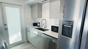 A modern kitchen with stainless steel appliances, a built-in microwave, and a sink. - Beautiful Modern House in Key Largo (Key Largo)