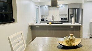 A modern kitchen with a central island, built-in appliances, and a dining area with a table. - Beautiful Modern House in Key Largo (Key Largo)