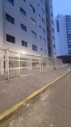Un edificio con fachada blanca, varias ventanas y un acceso con portón.