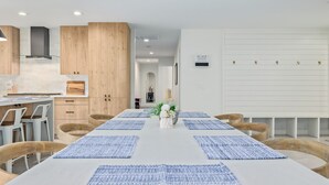 Una cocina moderna con armarios de madera, una isla central y un comedor con individuales azules y sillas de madera.