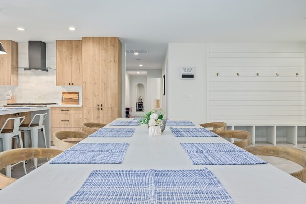 Une cuisine moderne avec des meubles en bois, un îlot central et un coin repas agrémenté de sets de table bleus et de chaises en bois.