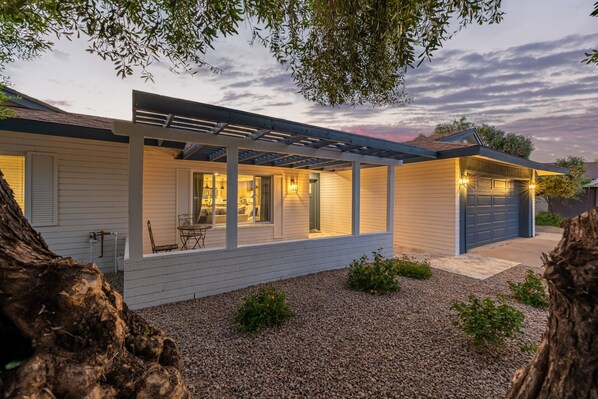 A modern house with a covered patio, a garage, and a gravel driveway.