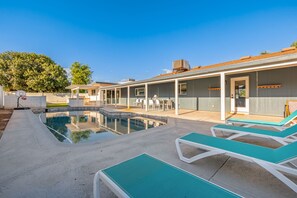 A modern outdoor pool area with lounge chairs and a covered patio.