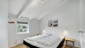 Une chambre à coucher avec un lit, une fenêtre, une table de chevet et des œuvres d’art murales.