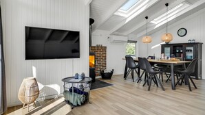 Un salon moderne doté d’un téléviseur à écran plat, d’une cheminée et d’un coin repas avec des chaises et une table.