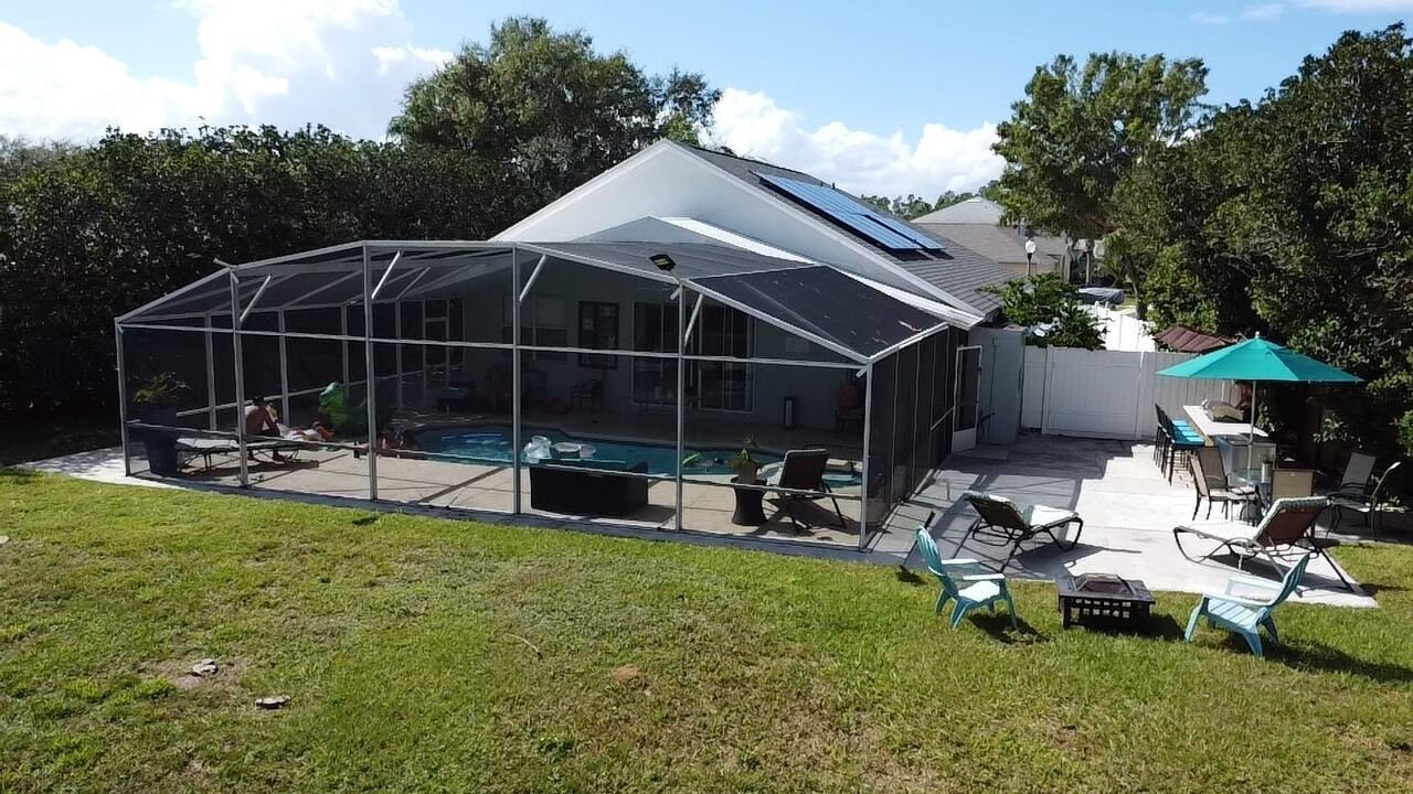 Una casa con un espacio exterior cubierto, una piscina y un patio con sillas y una mesa.