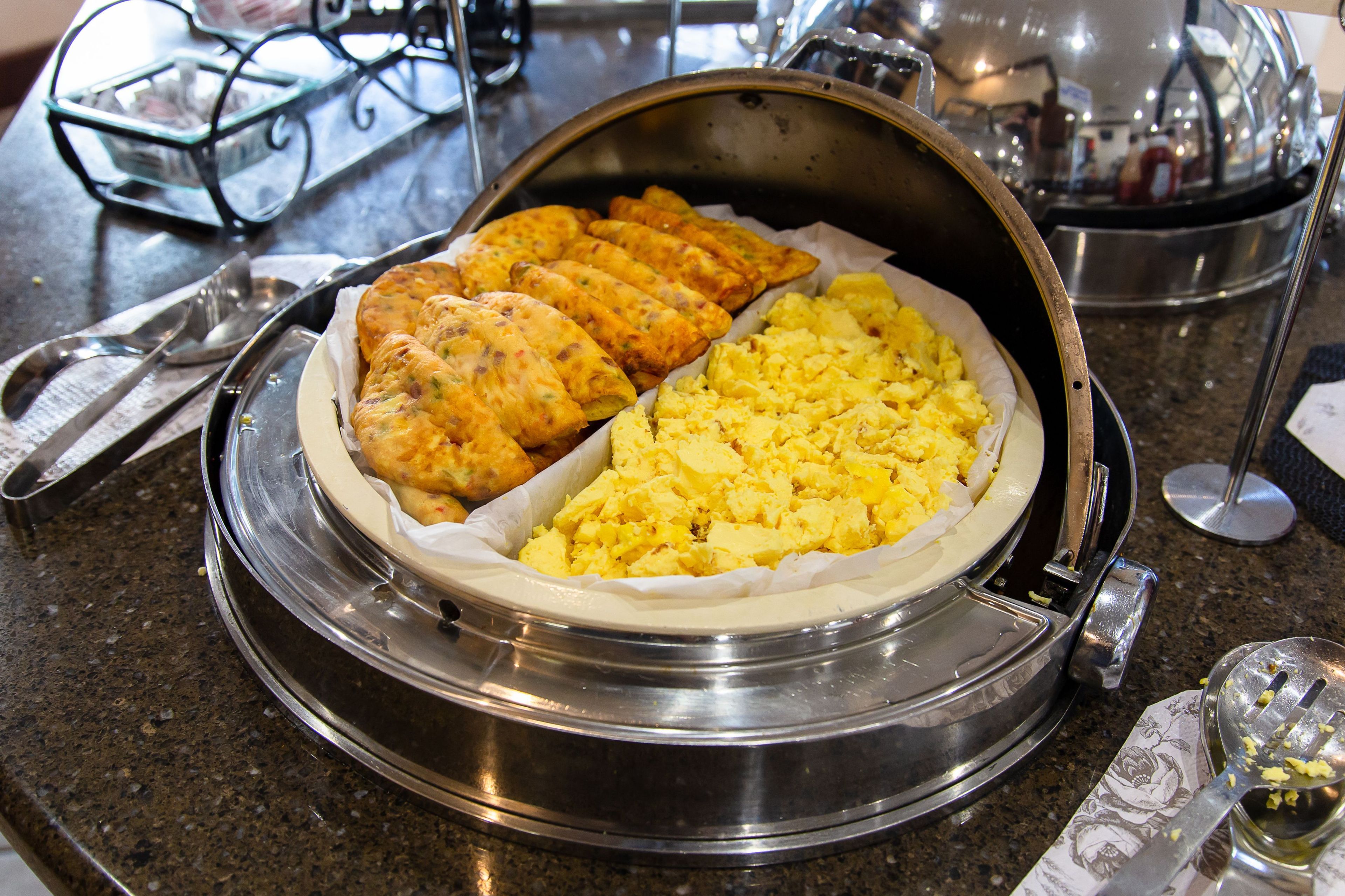 Breakfast buffet with scrambled eggs and baked goods.