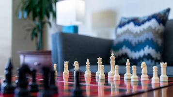 A chessboard with pieces in a living room setting.