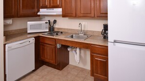 A kitchen with wooden cabinets, a white microwave, a stove, a sink, and a refrigerator. - Studio | Free Breakfast + Outdoor Pool (Plainfield)