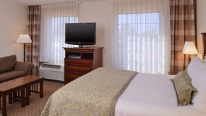 A hotel room with a bed, a TV, a sofa, a desk, and a lamp. - Studio | Free Breakfast + Outdoor Pool (Plainfield)