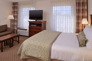Ein Hotelzimmer mit Bett, Fernseher, Sofa, Schreibtisch und Lampe.