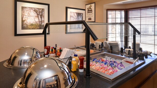 A breakfast buffet area with covered food stations, condiments, and a variety of yogurt cups. - Studio | Free Breakfast + Outdoor Pool (Plainfield)