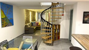 Ein modernes Wohnzimmer mit Wendeltreppe, einer Couch, einem Couchtisch und einem Bücherregal.