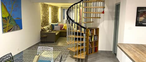 Una sala de estar moderna con una escalera espiral, un sofá, una mesa de centro y una estantería.