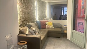Ein Wohnzimmer mit Steinwand, braunem Sofa, einem klaren Glastisch und einem kleinen Holztisch.