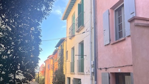 Eine enge Kopfsteinpflasterstraße gesäumt von farbenfrohen Gebäuden, jedes mit Fensterläden und Balkonen.