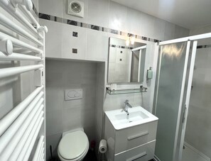 Ein Badezimmer mit Toilette, Waschbecken, Spiegel und Dusche.