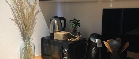 A kitchen counter with a microwave, a coffee maker, and a small potted plant.