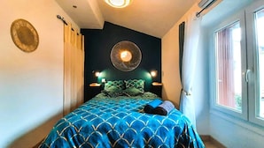 Camera da letto con un letto, un lampadario a parete e una finestra con tende.