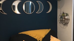 Una parete blu scuro con una serie di specchi a forma di luna e piante sospese.
