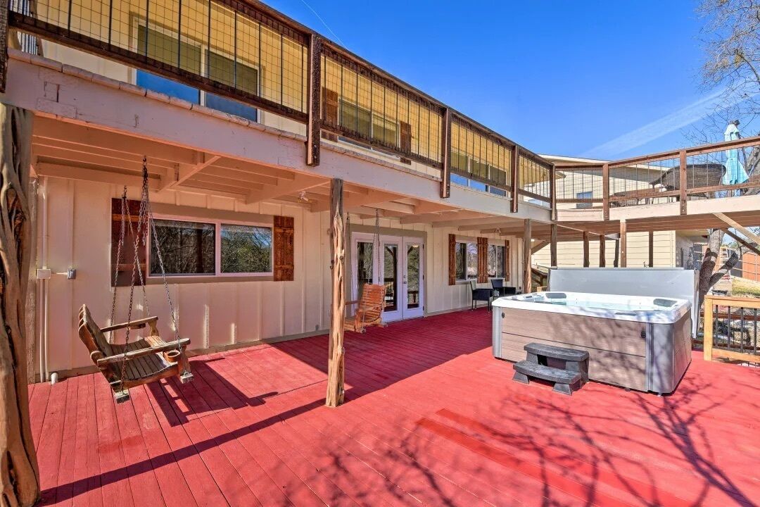Ein zweistöckiges Gebäude mit roter Terrasse, Whirlpool und Schaukelstuhl.