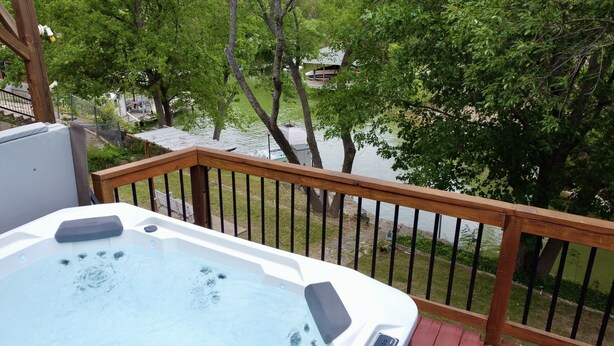 Un jacuzzi en una terraza de madera con vistas a un lago y árboles.