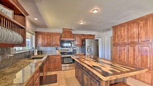 Una cocina con armarios de madera, encimeras de granito, electrodomésticos de acero inoxidable y una isla central.