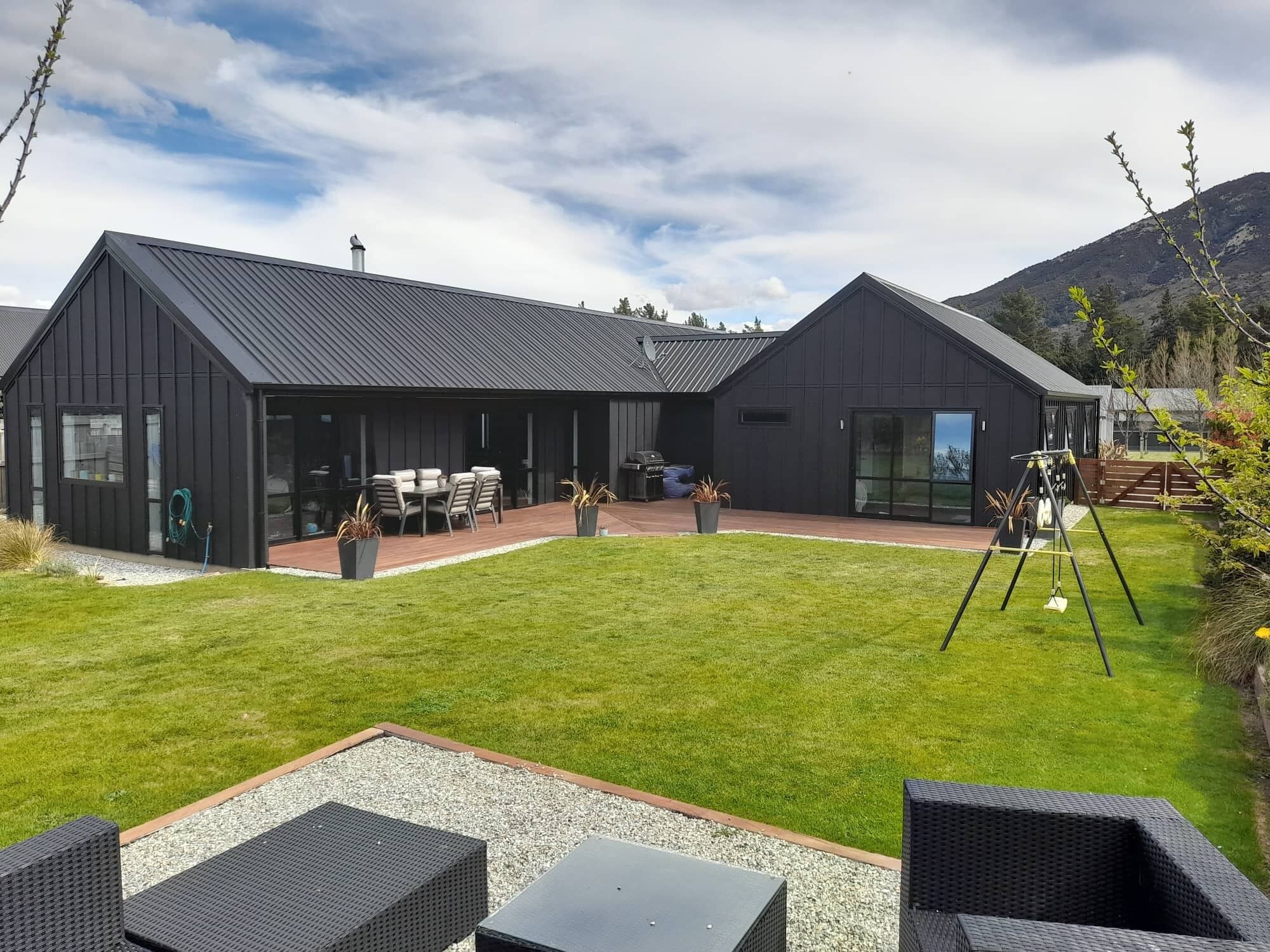 Une maison moderne dotée d’un grand patio, d’un espace salon extérieur couvert et d’une balançoire.