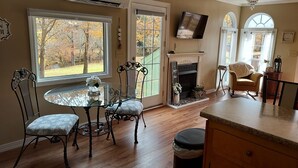 Ein gemütliches Wohnzimmer mit Kamin, einem darüber hängenden Fernseher und einem Essbereich mit Glastisch und Stühlen.
