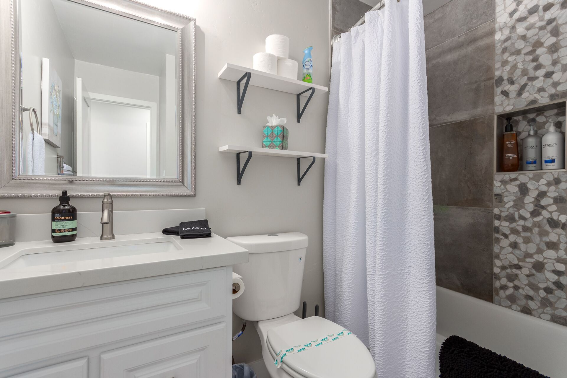 Un baño con lavamanos blanco, un espejo, inodoro y zona de ducha.