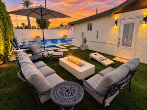 A backyard with a pool, outdoor seating, and a fire pit.