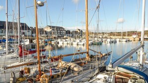 Una marina con diverse barche a vela ormeggiate, un edificio sullo sfondo e cielo sereno.