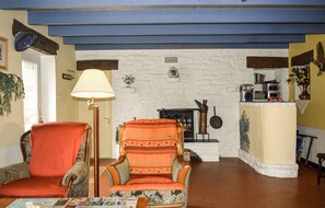 Ein gemütliches Wohnzimmer mit Kamin, zwei Sesseln, einer Stehlampe und einem Couchtisch.