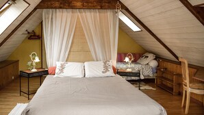 Una camera da letto mansardata accogliente con un letto grande, una sedia in legno e un comodino con una lampada.