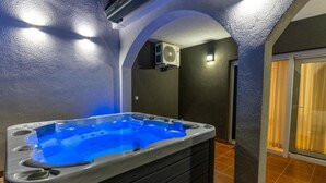 Una vasca idromassaggio con luce blu, una ventola a soffitto e un pavimento piastrellato.