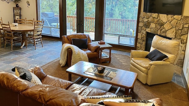 Un salón comedor amplio con chimenea, sofás de cuero, una mesa de centro y una zona de comedor con una mesa y sillas de madera.