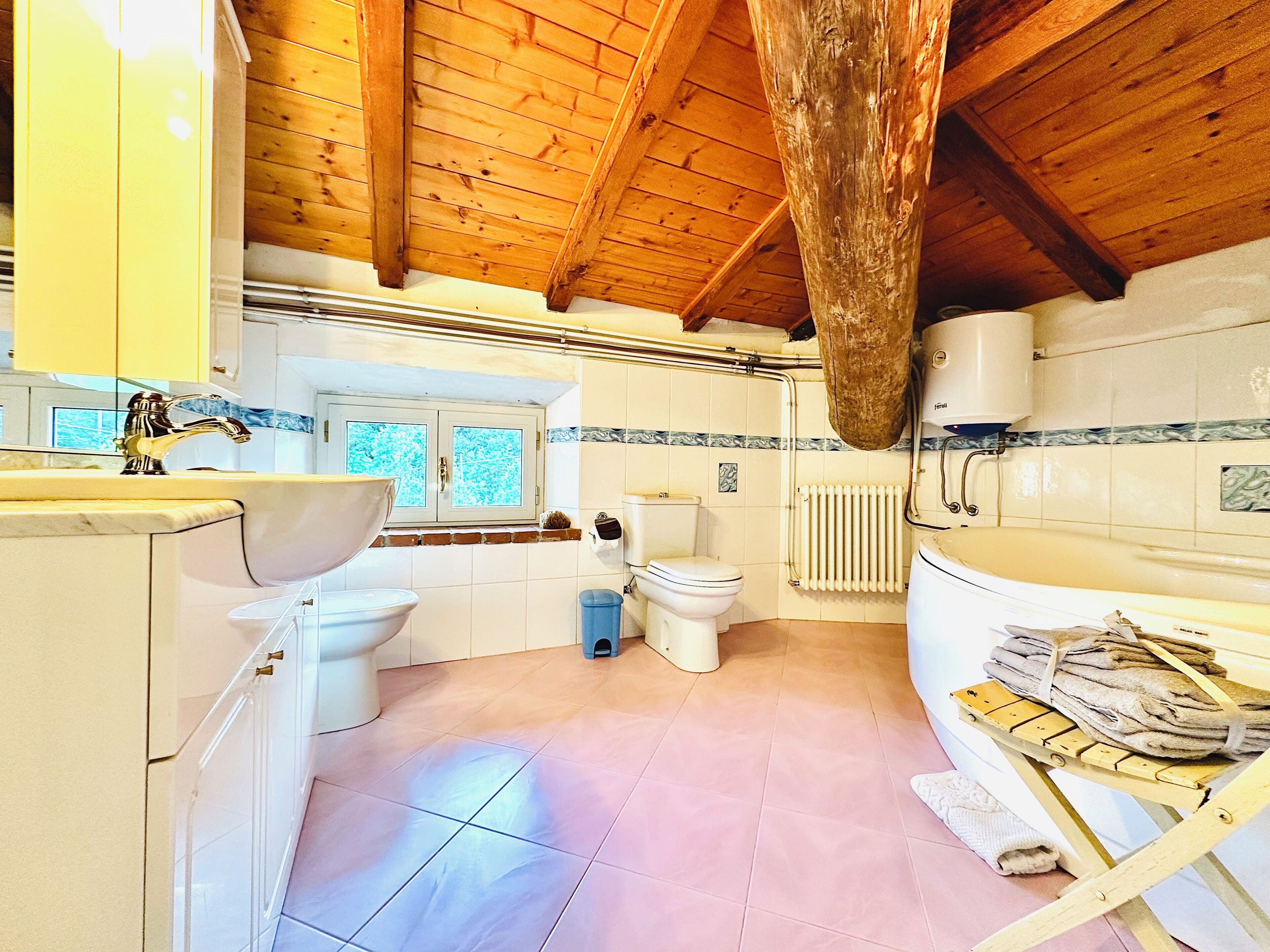 A bathroom with a wooden ceiling, a sink, a toilet, and a bathtub.