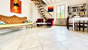 Un salón espacioso con techo alto, una escalera, un sofá, una mesa de comedor y una estantería.