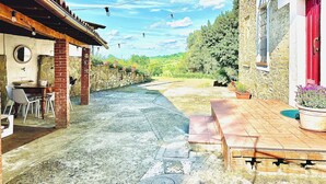 Un edificio rústico con fachada de piedra, puerta roja y un pequeño espacio al aire libre con mesa y sillas.