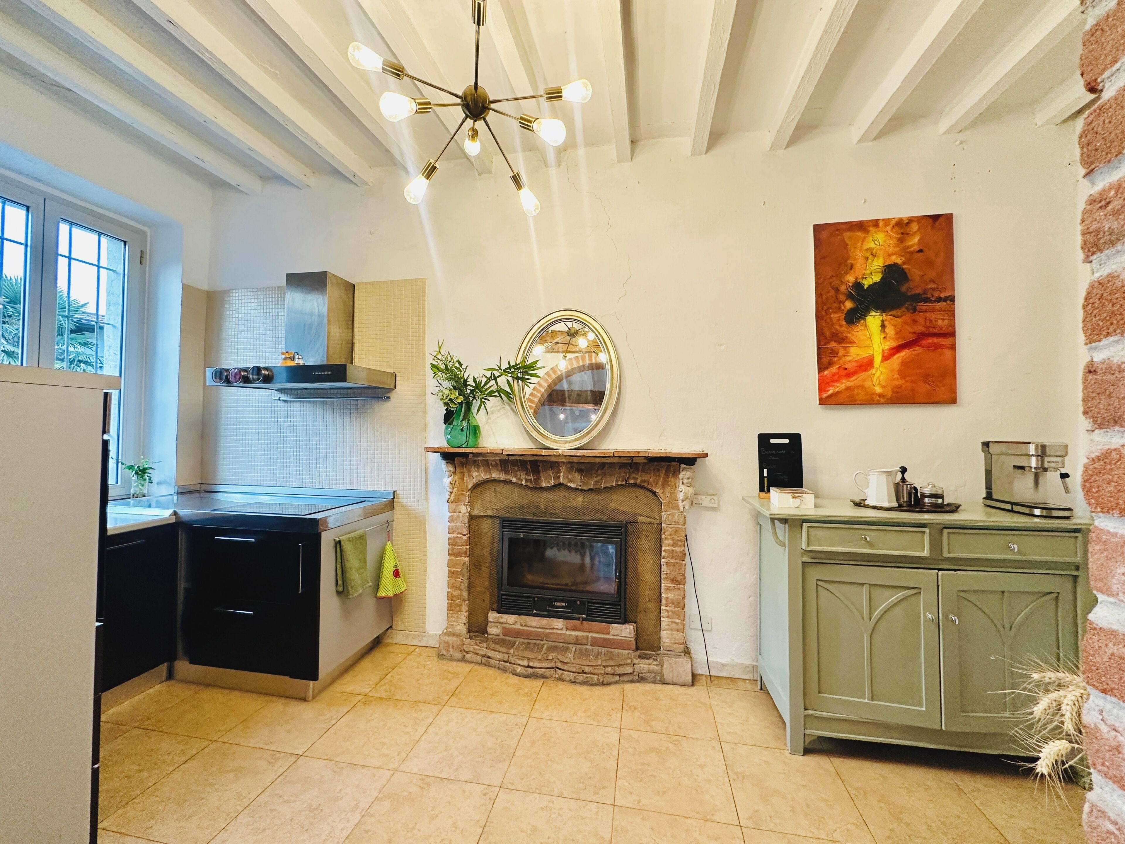 Una cocina con chimenea, cafetera y comedor con un armario verde.