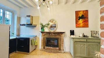 Una cocina con chimenea, cafetera y comedor con un armario verde.